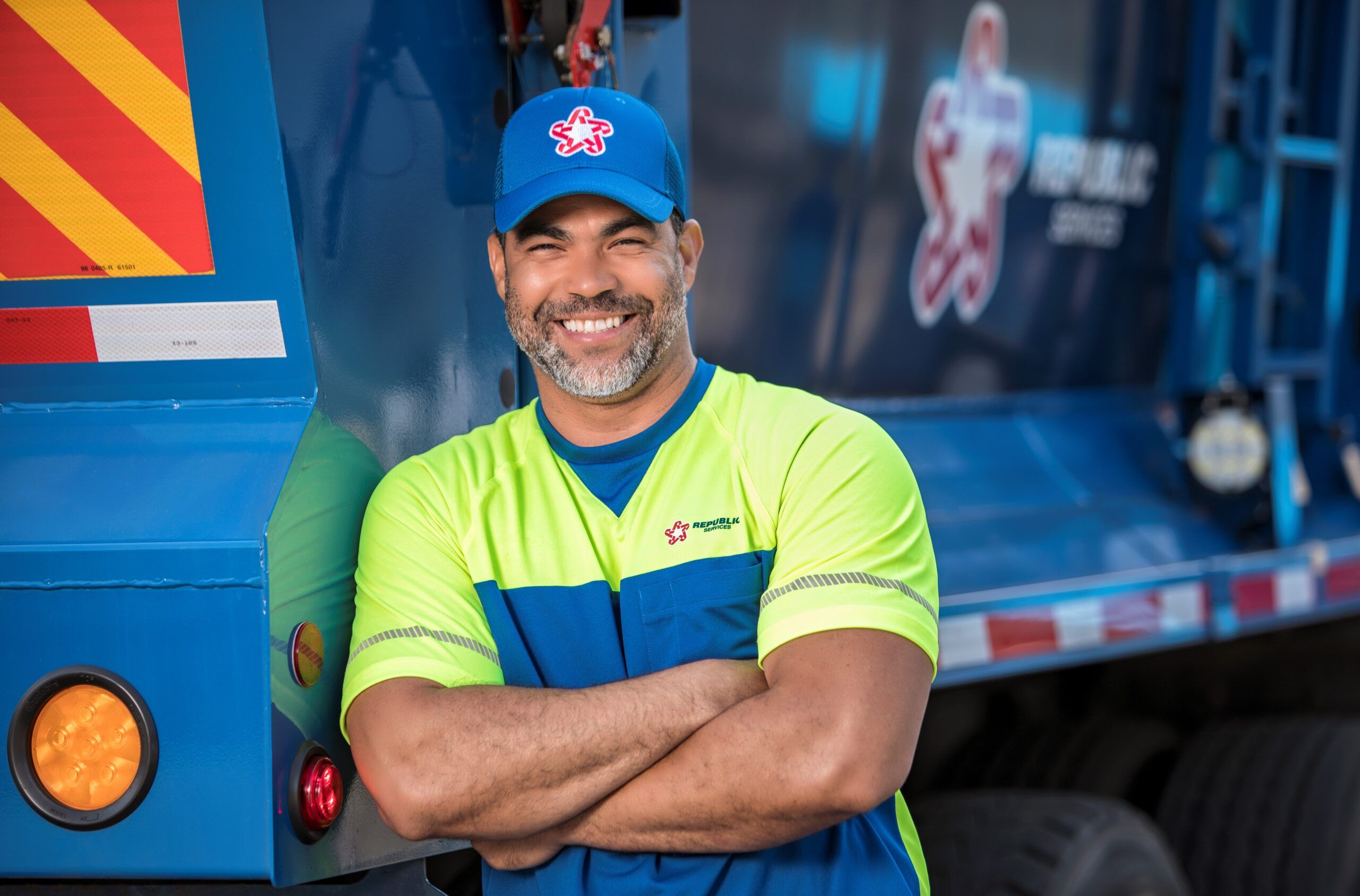 Republic Services driver leaning on a trash collection vehicle